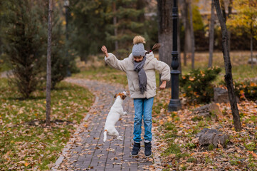 Fototapeta premium Caucasian girl playing with a dog for a walk in the autumn park. 