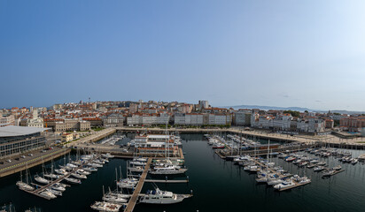 Obraz premium The harbor of La Coruna, Spain is situated near the downtown area of the city, featuring a marina where small boats and yachts are moored.