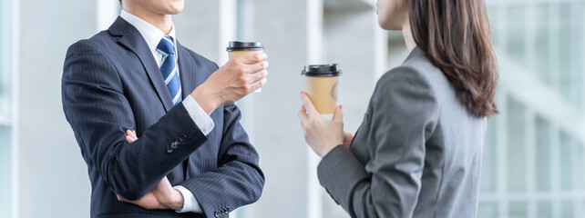 仕事の休み時間に飲み物を飲むビジネスマン男女