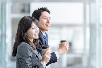 仕事の休み時間に飲み物を飲むビジネスマン男女