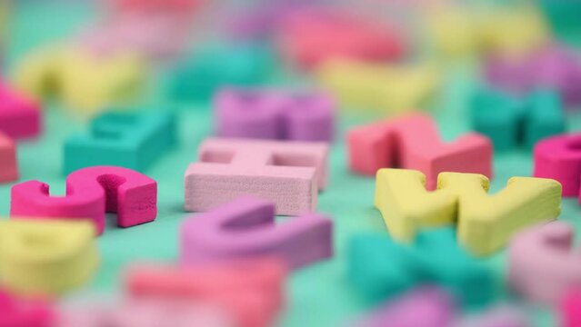 wooden colorful letters of the ABC alphabet rotate on a turquoise background closeup. the concept of learning and gaining knowledge. latin alphabet. back to school. macro.