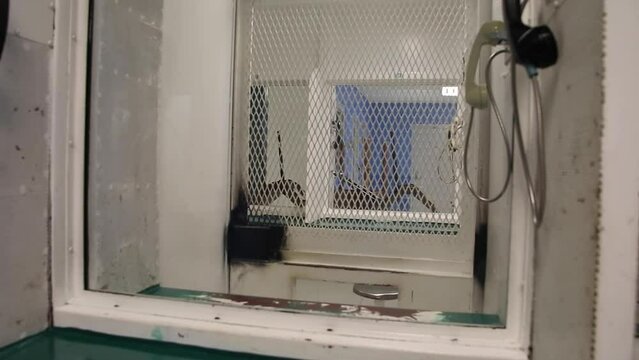 Prison phone booth in jail where prisoners can speak to family members during visitation through glass window