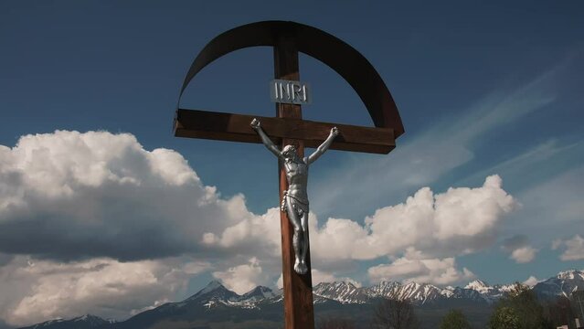 Cross with Jesus in front of mountains with clouds