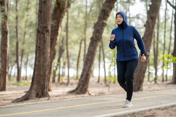 Fototapeta premium Happy cheerful Middle-aged Asian Muslim woman practicing exercise and stretching and enjoy jogging at the park close up with copy space. Modern muslim woman lifestyles and diversity concept.