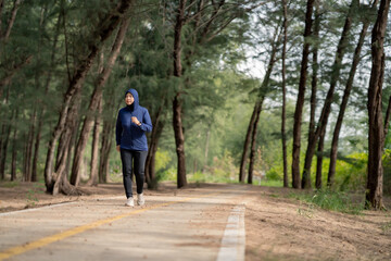 Fototapeta na wymiar Happy cheerful Middle-aged Asian Muslim woman practicing exercise and stretching and enjoy jogging at the park close up with copy space. Modern muslim woman lifestyles and diversity concept.