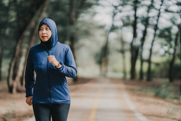 Happy cheerful Middle-aged Asian Muslim woman practicing exercise and stretching and enjoy jogging at the park close up with copy space. Modern muslim woman lifestyles and diversity concept.