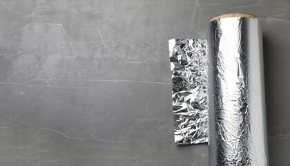 Roll of aluminum foil on grey table, top view. Space for text