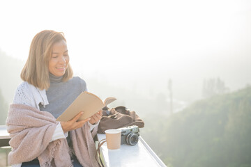 young woman reading book or bible near window and looking mountain view at countryside homestay in...