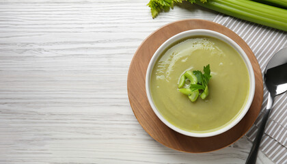 Bowl of delicious celery soup served on white wooden table, flat lay. Space for text