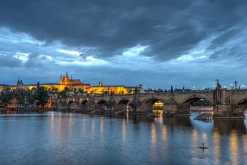 The castle and the famous Charles Bridge in Prague at dusk with dark clouds in the sky
