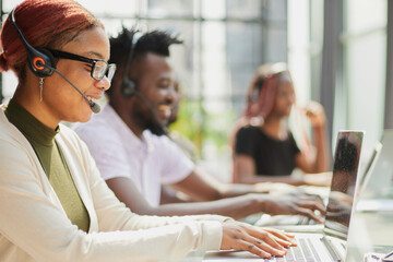 young call center operators sit at a laptop and help solve problems