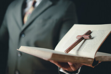 Asian man reading holy bible and crucifix according to divine teaching according to his faith and faith in god religious concept