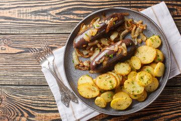 Traditional hot black pudding with fried onions and potatoes close-up on a plate on the table....