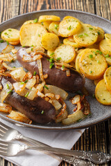 Blood sausage or black pudding with fried onions and potatoes closeup on the plate on the table....