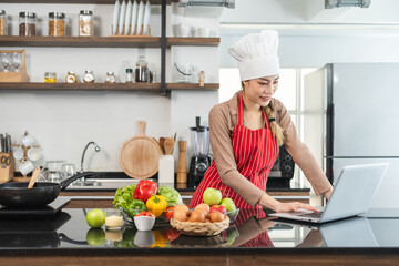 Young beautiful asian female chef cooking breakfast salad in the kitchen. Happy asian woman preparing healthy food with ingredient. Chef in uniform in the kitchen.