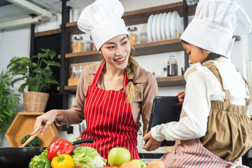 Happy moment asian mother and daughter cooking breakfast salad in the kitchen. Mom and daughter asian family having fun preparing healthy food vegetable. Positive parent and kid nice relationship