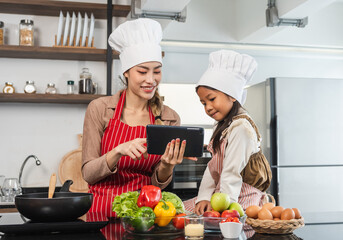 Happy moment asian mother and daughter cooking breakfast salad in the kitchen. Mom and daughter asian family having fun preparing healthy food vegetable. Positive parent and kid nice relationship