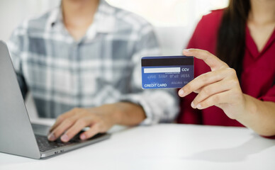 E-commerce Concept. Happy couple holding credit card enjoying doing online shopping and using laptop enter their card number in-app to purchase and payment in internet store