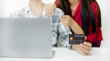 E-commerce Concept. Happy couple holding credit card enjoying doing online shopping and using laptop enter their card number in-app to purchase and payment in internet store