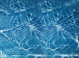 Blue water with ripples on the surface. Defocus blurred transparent blue colored clear calm water surface texture with splashes and bubbles. Water waves with shining pattern texture background.