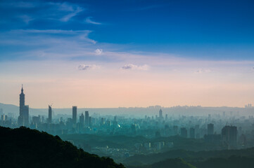Fototapeta premium Blue sky with white dynamic clouds over the city at dusk at sunset. View of the urban landscape from Dajianshan Mountain, New Taipei City, Taiwan