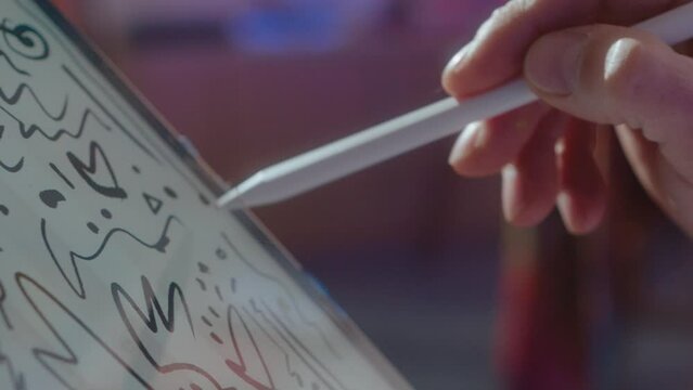 Close-up view of hands of talented male illustrator drawing sketch on touchscreen of a digital tablet with stylus pen