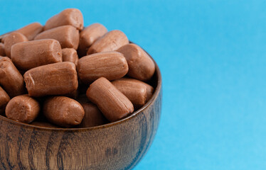 A Pile of Freeze Dried Chocolate Candy Rolls Isolated on a Blue Background
