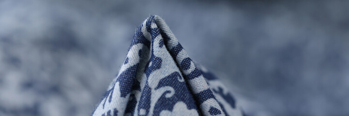 Blue fabric with white geometric ornament close up.