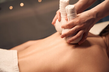Massotherapist giving upper back hot compress massage to patient - obrazy, fototapety, plakaty
