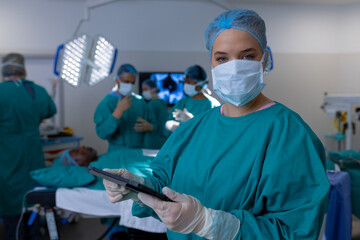 Portrait of caucasian female surgeon wearing surgical gown in operating theatre at hospital