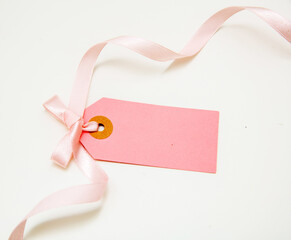 Blank pink price tag isolated on white background. Pastel color empty gift card and curly ribbon bow,