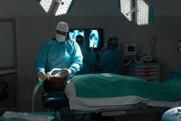 Biracial male surgeon placing anaesthetic face mask on patient in operating theatre at hospital