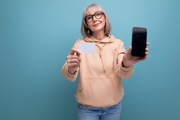portrait of a confident 60s woman with gray hair who masters cashless payments by credit card on a...