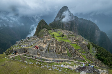 Macchu Picchu ruins surrounded by clouds and a stormy sky
