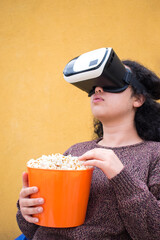 Woman wearing vr headset and eating popcorn from orange pot