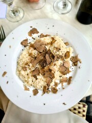 Risotto with truffles on a white plate with set table background