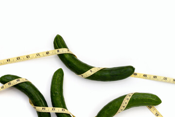 Measuring tape around cucumbers on white background.
