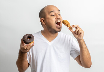 Asian man eating Sweet donut dessert. Hungry Young man holding chocolate donut unhealthy food. Food...