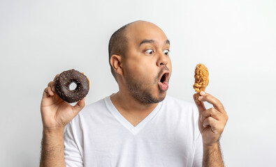 Asian man eating Sweet donut dessert. Hungry Young man holding chocolate donut unhealthy food. Food...