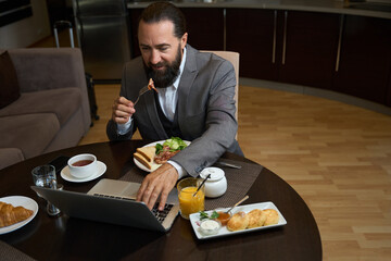 Bearded man has breakfast in a hotel room
