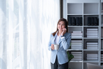 Fototapeta premium Happy of young smiling businesswoman looking at smartphone cellphone laptop bookkeeping computer, an enjoy successful accountant young owner calculation taxes rates meet firm law data with computer 