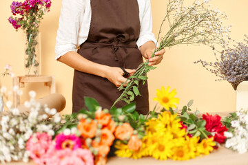 Professional floral services. Delicate floral craftsmanship. Organic flower arrangements. Assorted bouquet choices. Woman florist making bouquet of fresh flowers isolated over beige background