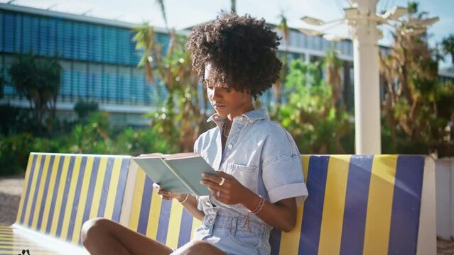 Teen girl studying textbook sitting campus bench close up. Student reading book.