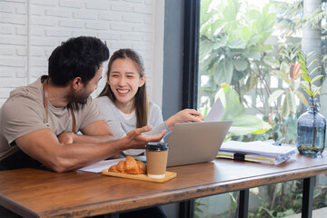 Lifestyle small business couple happy working together in cafe coffee shop, cheerful wife talking to husband or consulting project start-up planning, man and woman doing paperwork paying tax online