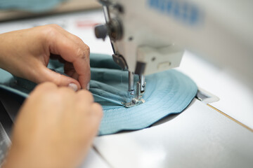 workers in an industrial garment factory sew clothes on sewing machine
