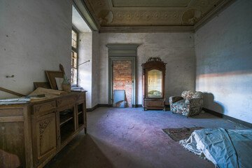 an old armchair and a broken wardrobe in an abandoned mansion