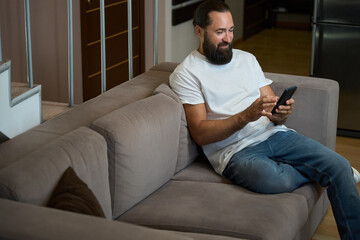 Smiling man spends evening chatting online on mobile phone