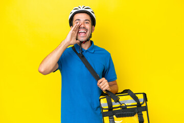 Young handsome man with thermal backpack over isolated yellow background shouting with mouth wide open