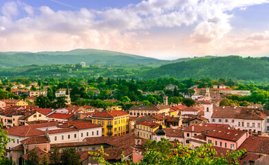 Fototapeta premium travel summer view from hill to a nice european town with amazing buildings, green hills and mountains with amazing cloudy evening sky on background