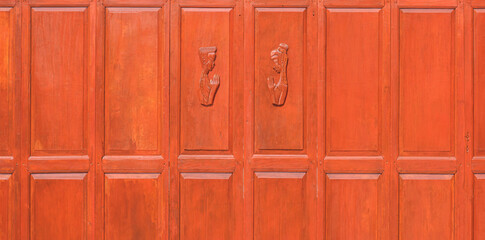 Fototapeta premium Decorative vintage wooden wall made from the old hardwood folding door material with male and female wooden carved in pay respect gesture on surface, home renovation and improvement concept